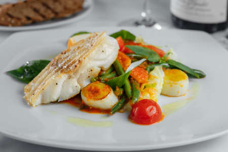 baked fish with asparagus on a white plateの写真素材