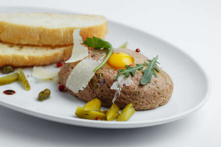 Meat cutlet with pickled cucumbers and bread on a white plate closeupの写真素材