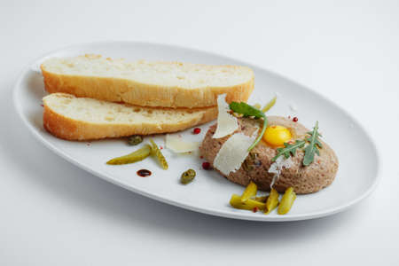 Meat cutlet with pickled cucumbers and bread on a white plateの写真素材