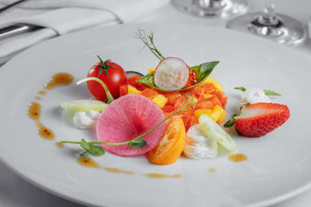 fruit tartare with slices of salmon, red caviar on a white plateの写真素材