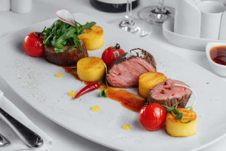veal with tomatoes, red peppers on a white plateの写真素材