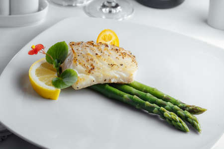 fish with asparagus on a white plateの写真素材