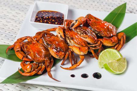 Cooked crab with sauce and lime on a white plateの写真素材
