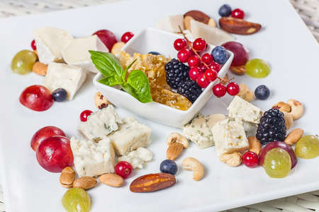 Berries, cheese, nuts and honey on a plateの写真素材