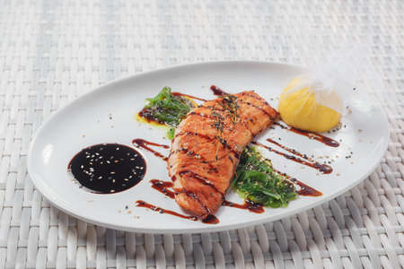a piece of baked fish and salad Chuka on a white plateの写真素材