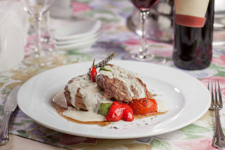 Baked meat with vegetables and sauce on a plateの写真素材
