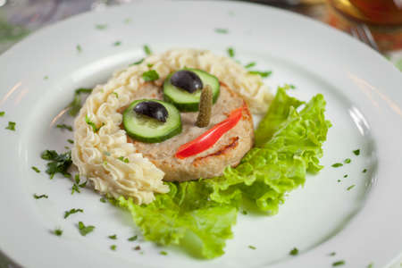 Cutlet with mashed potatoes and vegetables in the form of facesの写真素材