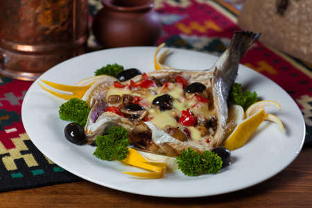 stuffed fish with olives and herbs on a plateの写真素材