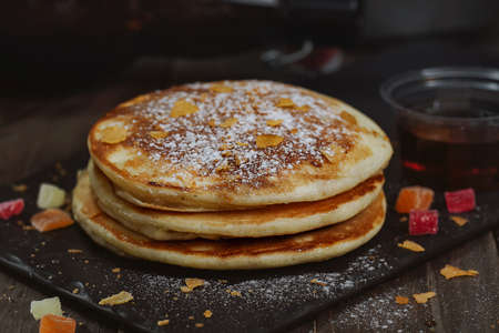 pancakes with honey and candied fruit for breakfast on a wooden table