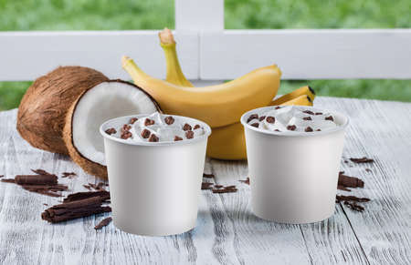 ice cream in cups with coconut and banana flavor on a white wooden tableの写真素材