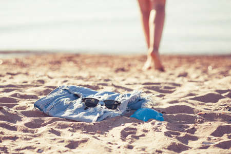 Blurred photo with shallow depth of field. Vacation holidays concept - silhouette of sun-tanned woman legs shoeless that walks along seashore. Rear view from below.の写真素材