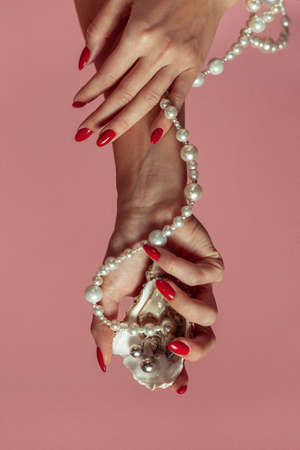 female hand holds oyster shell with pearls from jewelry.の写真素材
