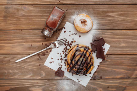 Tasty cinnamon bun and newspapers on tableの写真素材