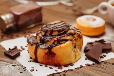 Tasty cinnamon bun and newspapers on tableの写真素材