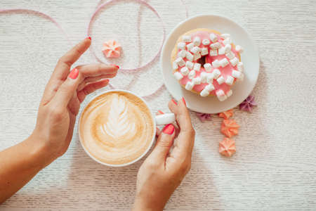Manicured woman's hand holding white cup of coffee. Trendy summer spring pink marble nail design.の写真素材