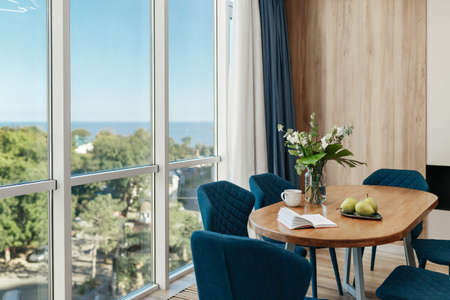 wooden table for lunch and negotiations decorated with flowers and pears panoramic window overlooking the seaの写真素材