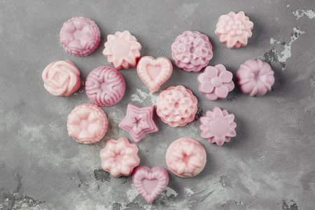 A small handmade soap is laid out in the shape of a heart on a concrete floor. Lots of pink soap