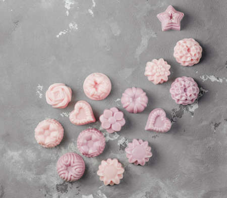 A small handmade soap is lined with ornaments on the concrete floor. Lots of pink soapの写真素材