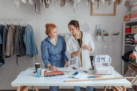 Fashion designer sewing fabrics with assistant. two young designers work in a bright studio, have opened their own business and are ready to take orders. Beginning of workの写真素材