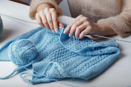 woman knits handmade woolen blue sweater on the tableの写真素材