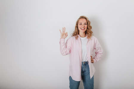 The girl with the curly hair on the white background shows that everything is OKの写真素材