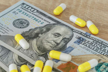 Money for drugs, a concept, 100 dollars and pills close-up