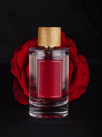 a bottle of perfume against a large red flower against a dark backgroundの写真素材
