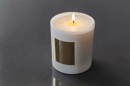 a candle in a cup in close-up with a gold-coloured labelの写真素材