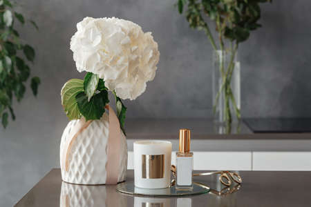 Stylish tender composition with candles, wick trimmer, lollion and flowers on table against gray background, space for text. Cozy interior elementの写真素材