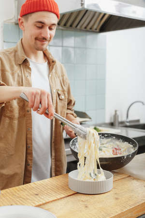 man cooking pasta on his kitchen in a cafeの写真素材