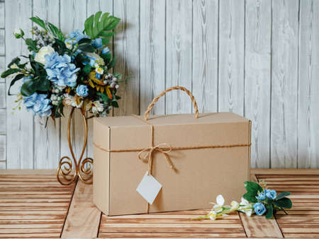 a gift with a business card on a wooden table decorated with flowersの写真素材