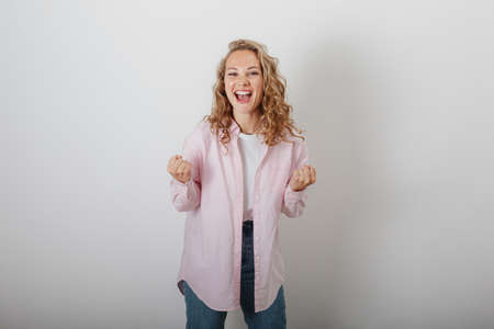 A girl with curly hair in a white background rejoices in successの写真素材