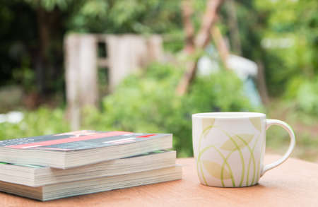 a cup of coffee and books on the wooden tableの写真素材