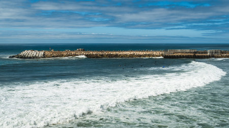 The bay at Ericeira's rocky pier, where surfers learn to catch waves that go to the sandy beach, Portugal.の写真素材