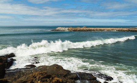 The bay at Ericeira's rocky pier, where surfers learn to catch waves that go to the sandy beach, Portugal.の写真素材