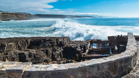 Atlantic Ocean waves whipping white foam against the rocky shore, Ericeira, Portugal.の写真素材