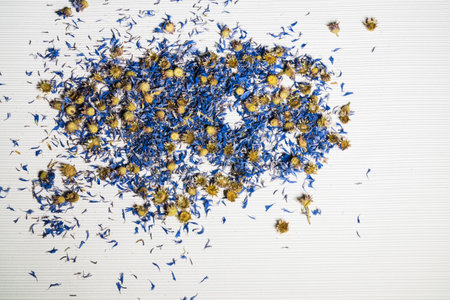 Dried cornflower flowers on a white background, decor; abstract combination of yellow flower heads and blue petals.の写真素材