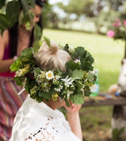 Summer solstice wreath on head, oak leaf wreath with white wildflowers, handmade, individual parts in focus, summer day.の写真素材