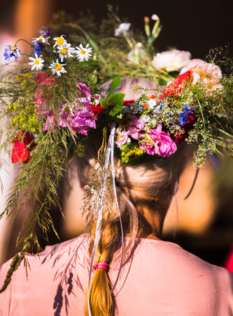 Summer solstice wreath of wild and garden flowers for a girl with blond hair and a braid on her...