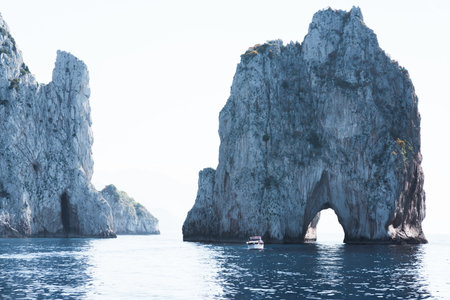 Capri, Italy - 04.29.2025: The famous Faraglioni rocks on the island of Capri, Italy. Close-up view from a nearby boat against a sky background.の写真素材