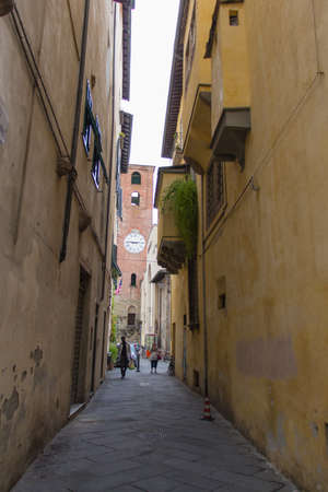 Italy, Lucca - September 18 2016: the detailed view of narrow street and antique clock tower in Lucca on September 18 2016 in Lucca, Tuscany, Italy.のeditorial素材