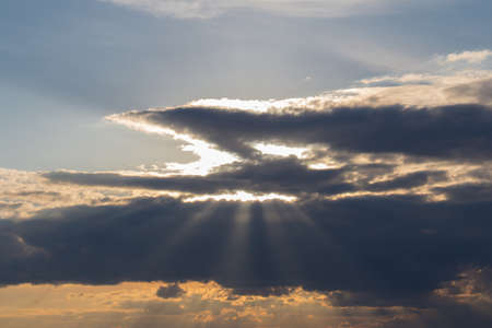 The view of the sunset light beams coming through clouds. Skyscape.