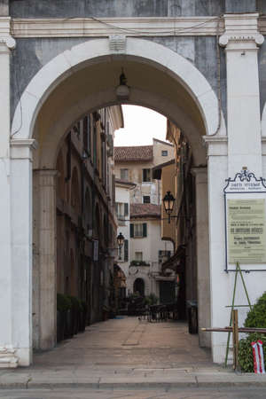 Brescia, Italy - August 1 2018: the view through an arch on a narrow street in the city center of Brescia on August 1 2018, Lombardy, Italy.のeditorial素材