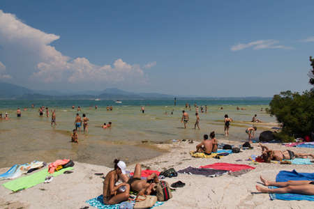 Italy, Lombardy - August 05 2018: the view of people taking sun at Jamaica Beach on Lake Garda on August 05 2018 in Sirmione, Italy.のeditorial素材