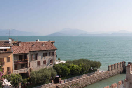 Italy, Lombardy - August 05 2018: the view of the Old Town on Garda lake with horizon line on background on August 05 2018 in Sirmione, Italy.のeditorial素材