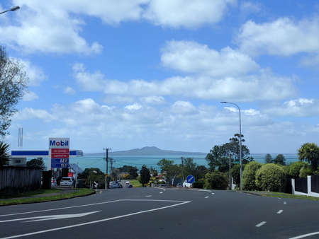 Auckland suburb, New Zealand - October 30 2019: the view of picturesque landscape with asphalt road, blue sea and Rangitoto Island on background on October 30 2019 in Auckland, New Zealand.のeditorial素材