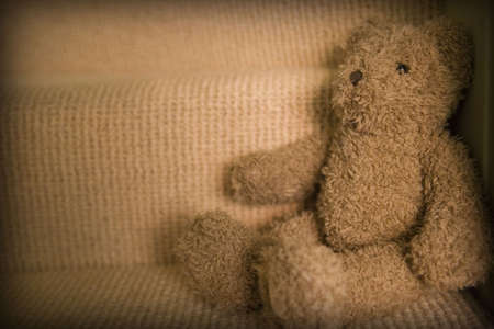 Child's teddy bear sitting on staircase with copy spaceの写真素材