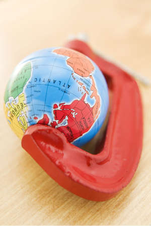 Political Globe Squeezed In Clamp On Wooden Surfaceの写真素材