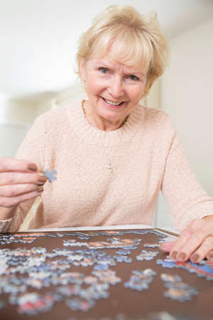 Senior Woman Relaxing With Jigsaw Puzzle At Homeの写真素材