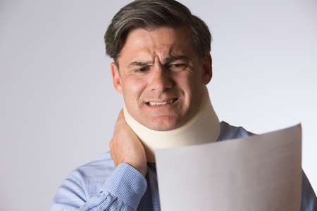 Studio Shot Of Man Wearing Neck Brace Reading Letter